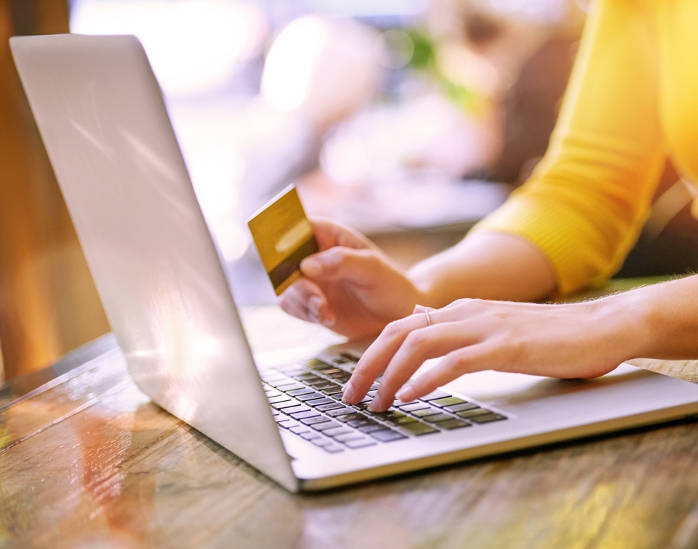 woman holding credit card near laptop